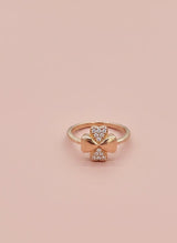 Gold ring with diamond accents on a pink background