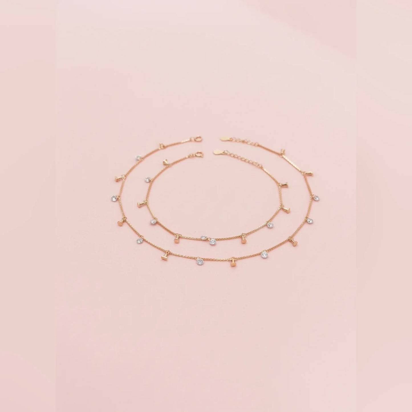 Gold anklet with small beads on a light pink background