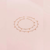 Gold anklet with small beads on a light pink background