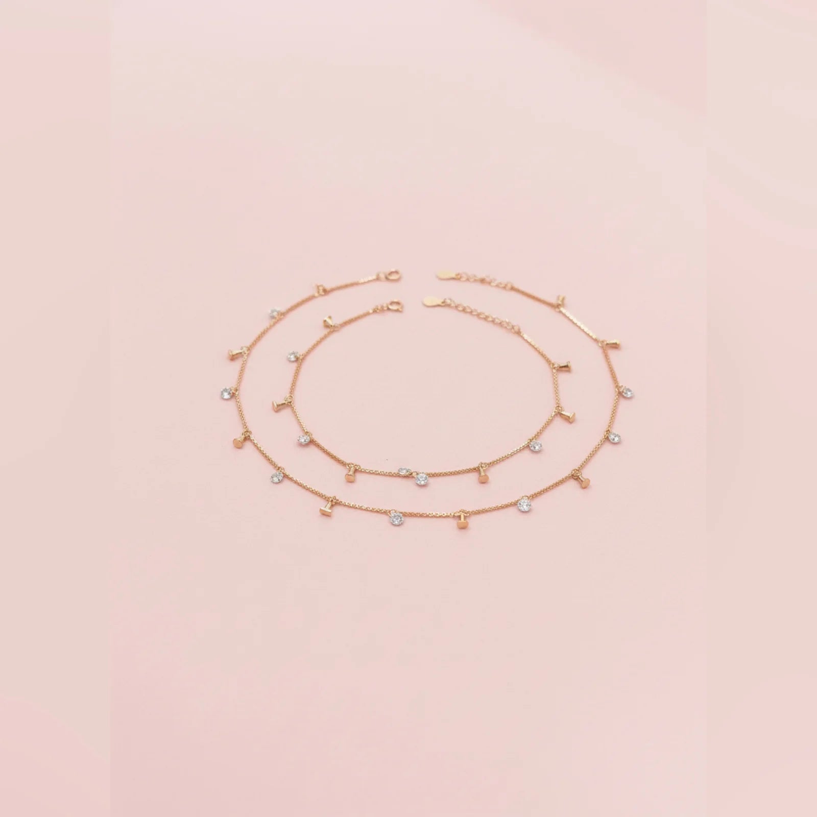 Gold anklet with small beads on a light pink background