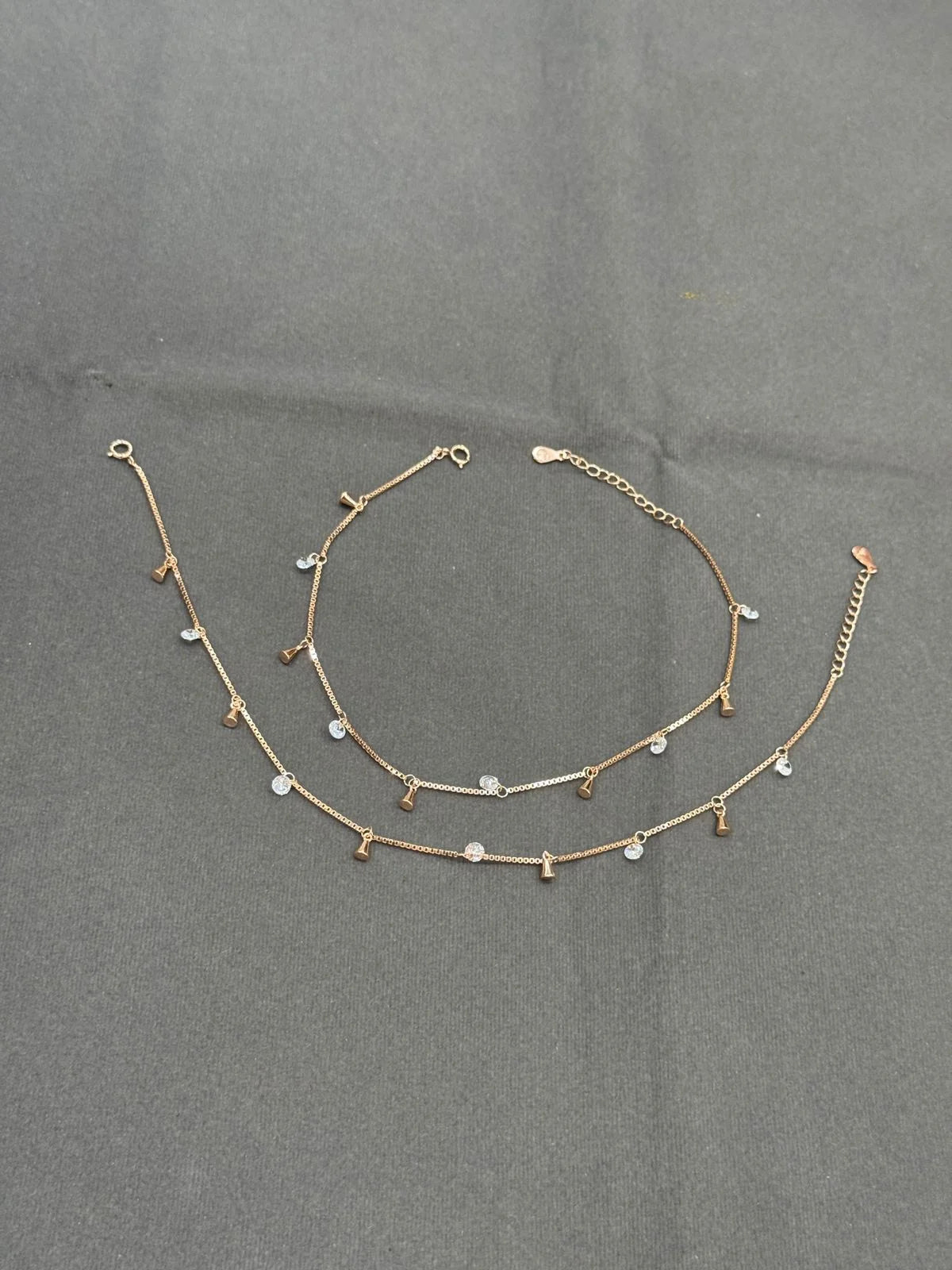 Gold anklet with small beads on a gray background