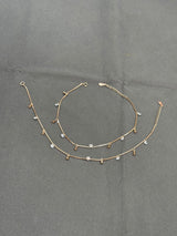 Gold anklet with small beads on a gray background