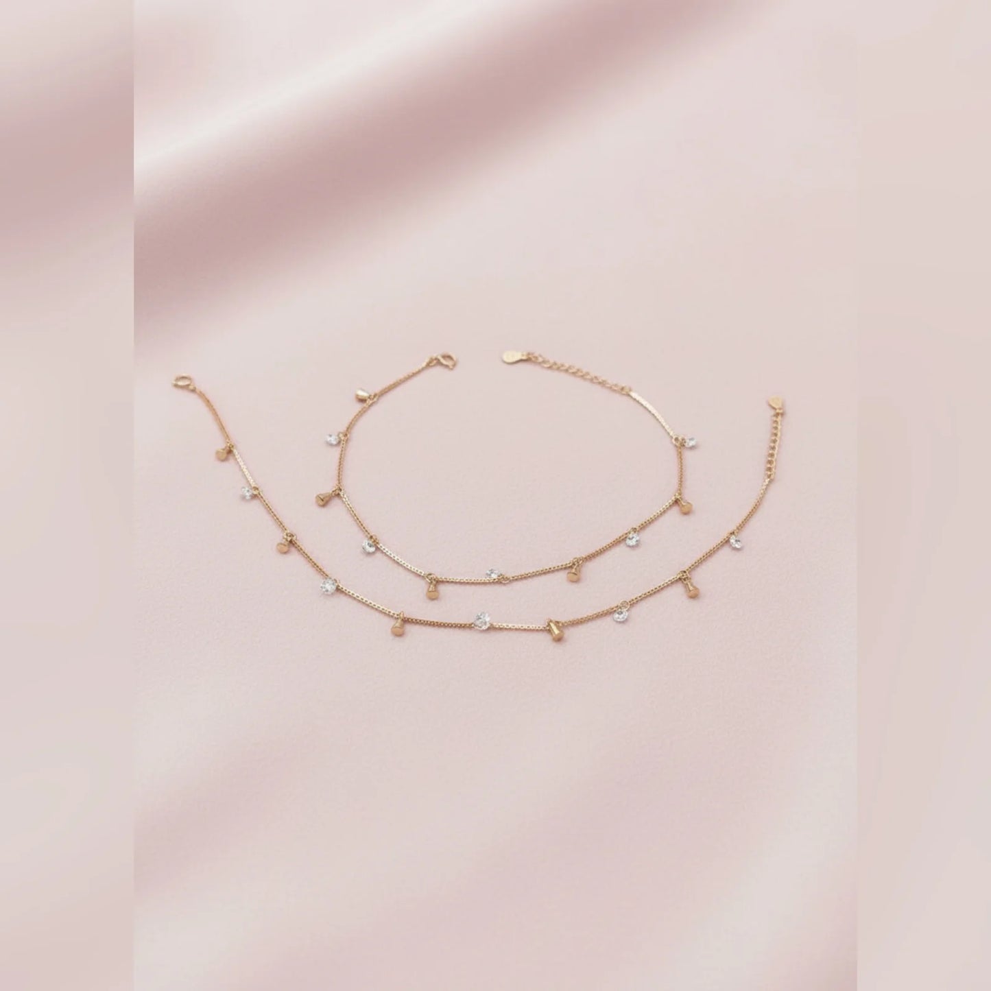 Gold anklet with small beads on a pink background