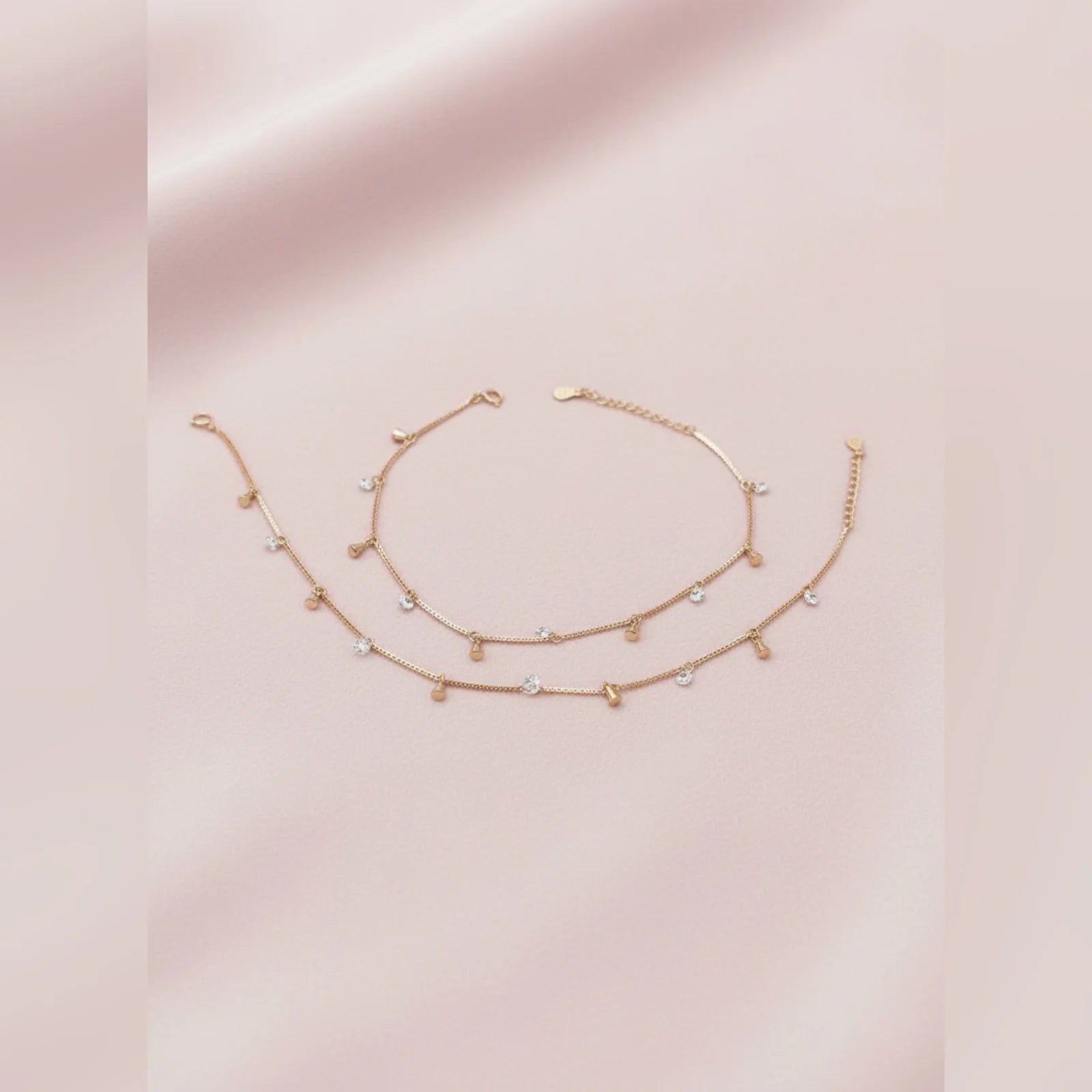 Gold anklet with small beads on a pink background