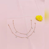 Two layered gold necklaces on a pink background with a yellow flower.
