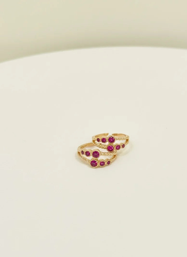 Gold toe rings with red gemstones on a white surface