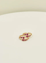 Gold toe rings with red gemstones on a white surface
