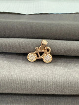 Gold bicycle-shaped pendant on a gray fabric background