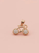 Rose gold bicycle pendant with embedded stones on a pink background