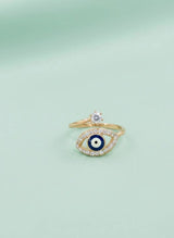 Gold ring with eye design and diamond on a light green background