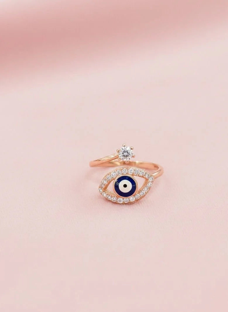 Rose gold ring with eye design on a pink background