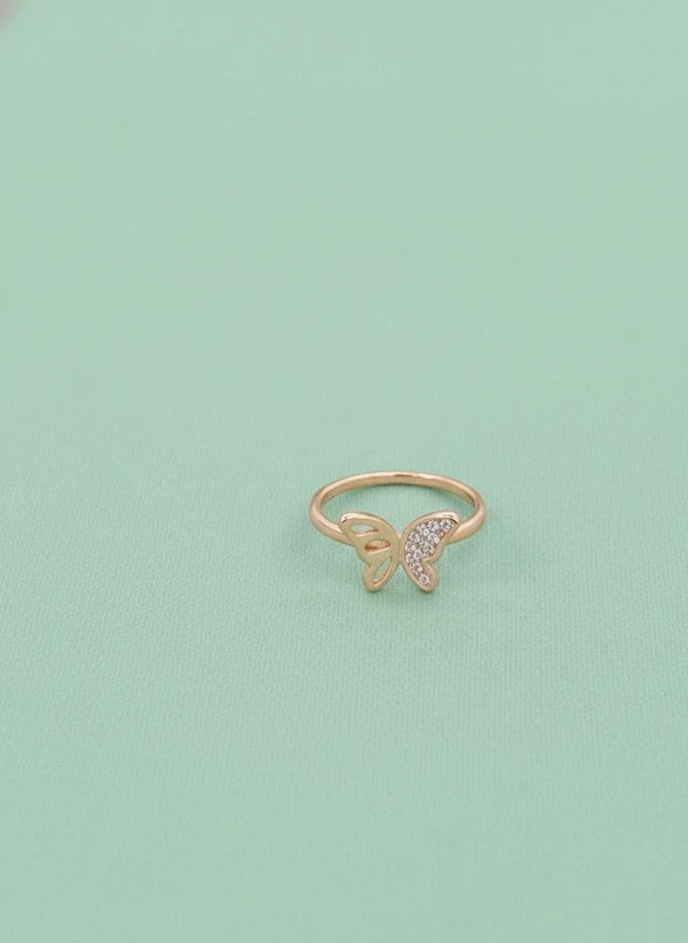 Gold butterfly ring on a light green background