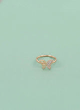 Gold butterfly ring on a light green background