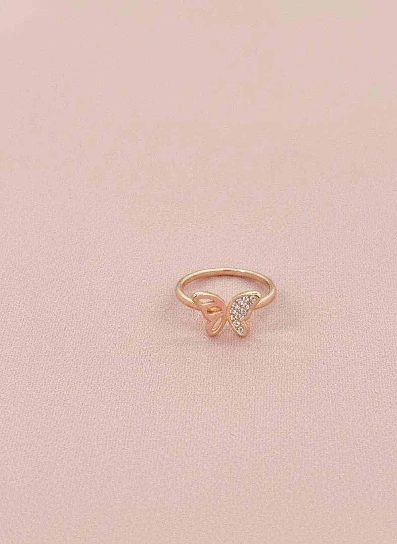 Rose gold butterfly ring with small diamonds on a pink background
