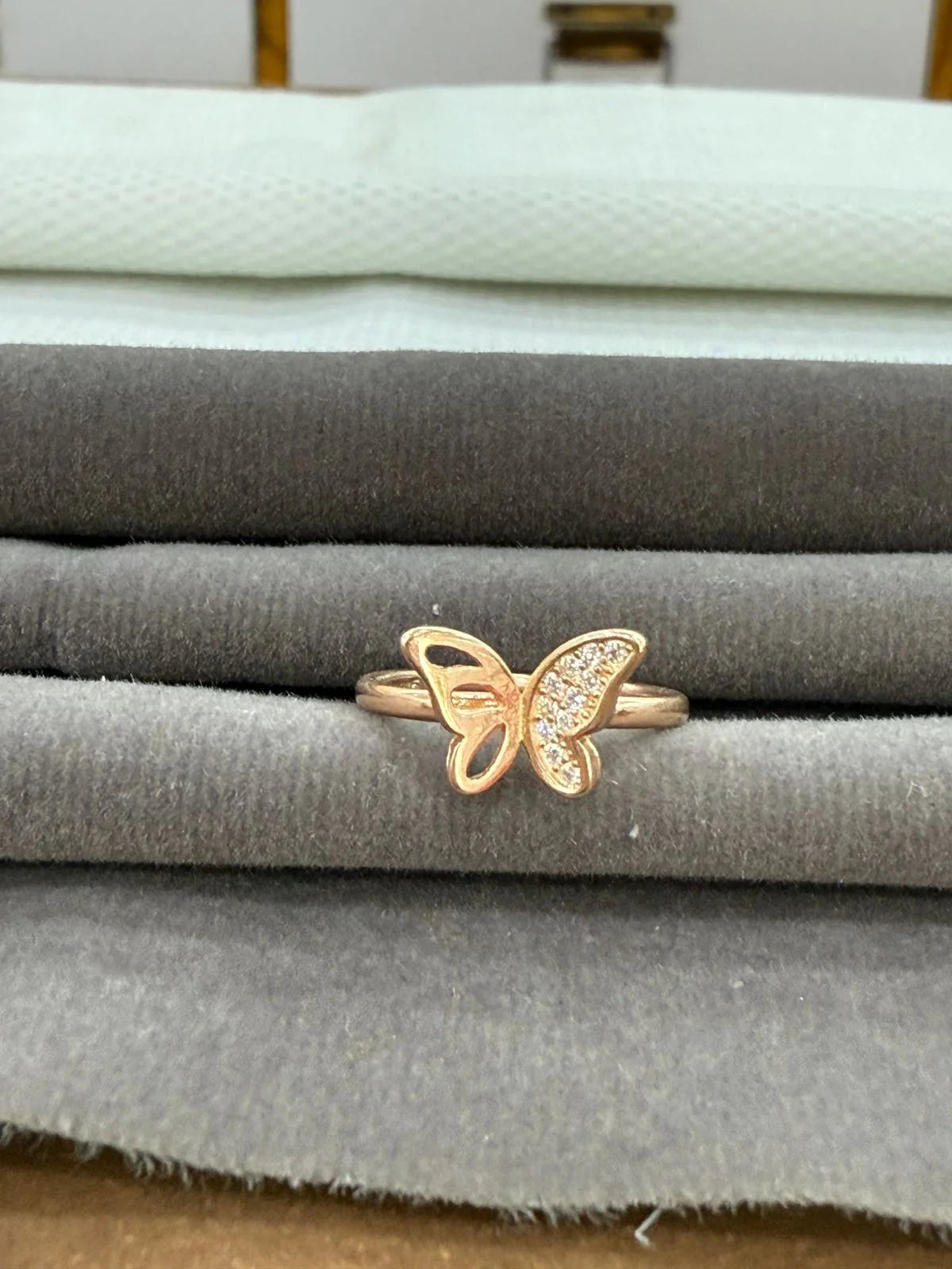 Gold butterfly ring on a stack of fabric swatches