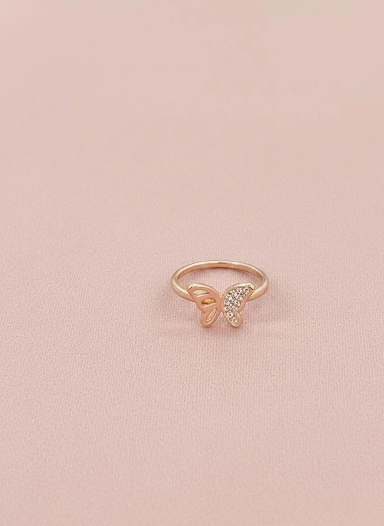 Rose gold butterfly ring with small diamonds on a pink background