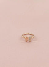 Rose gold butterfly ring with small diamonds on a pink background
