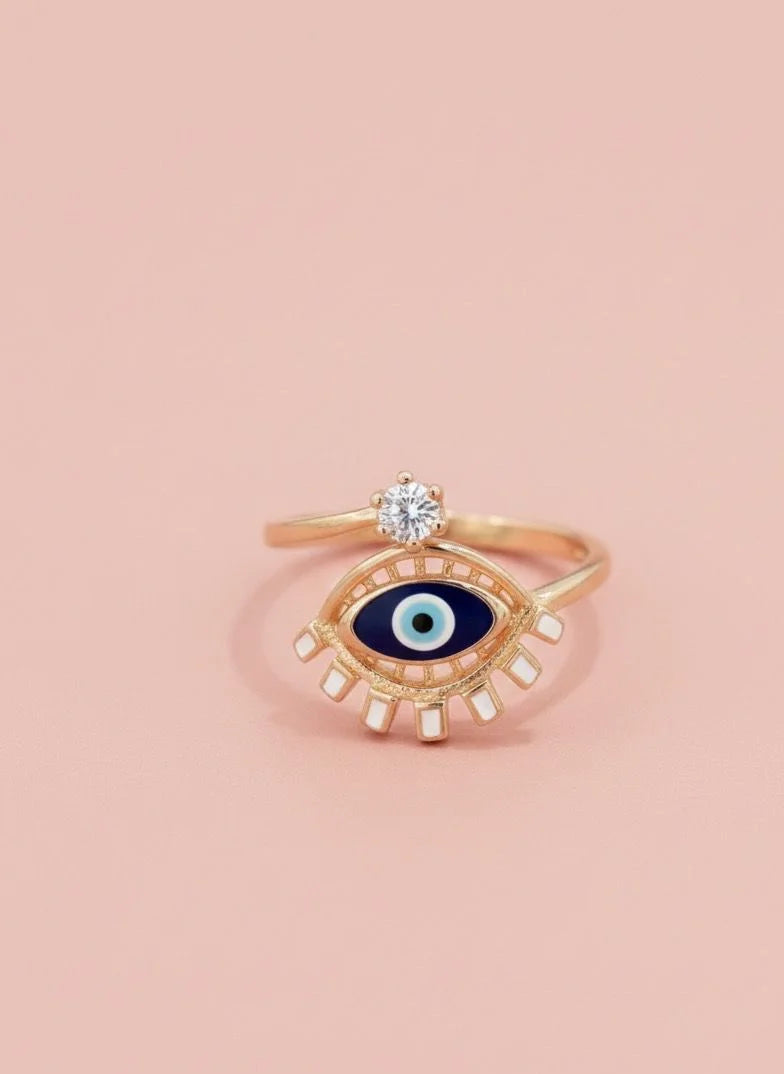 Gold ring with eye design on a pink background