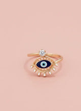 Gold ring with eye design on a pink background