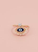 Gold ring with eye design on a pink background