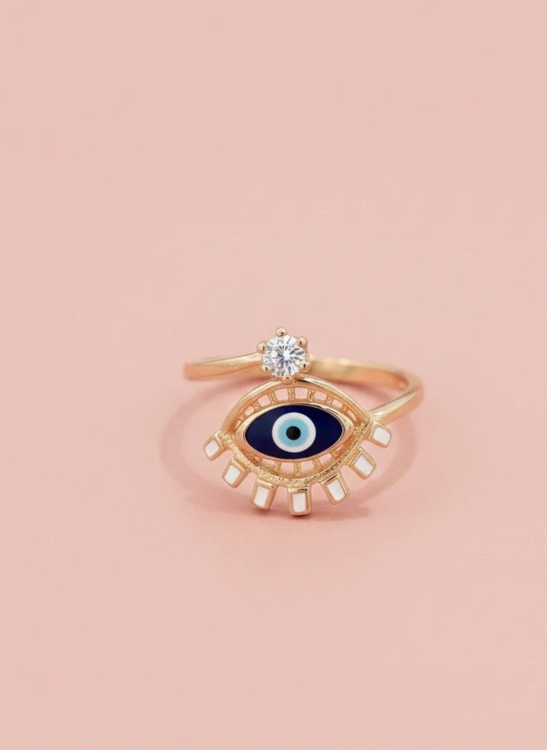 Gold ring with eye design on a pink background