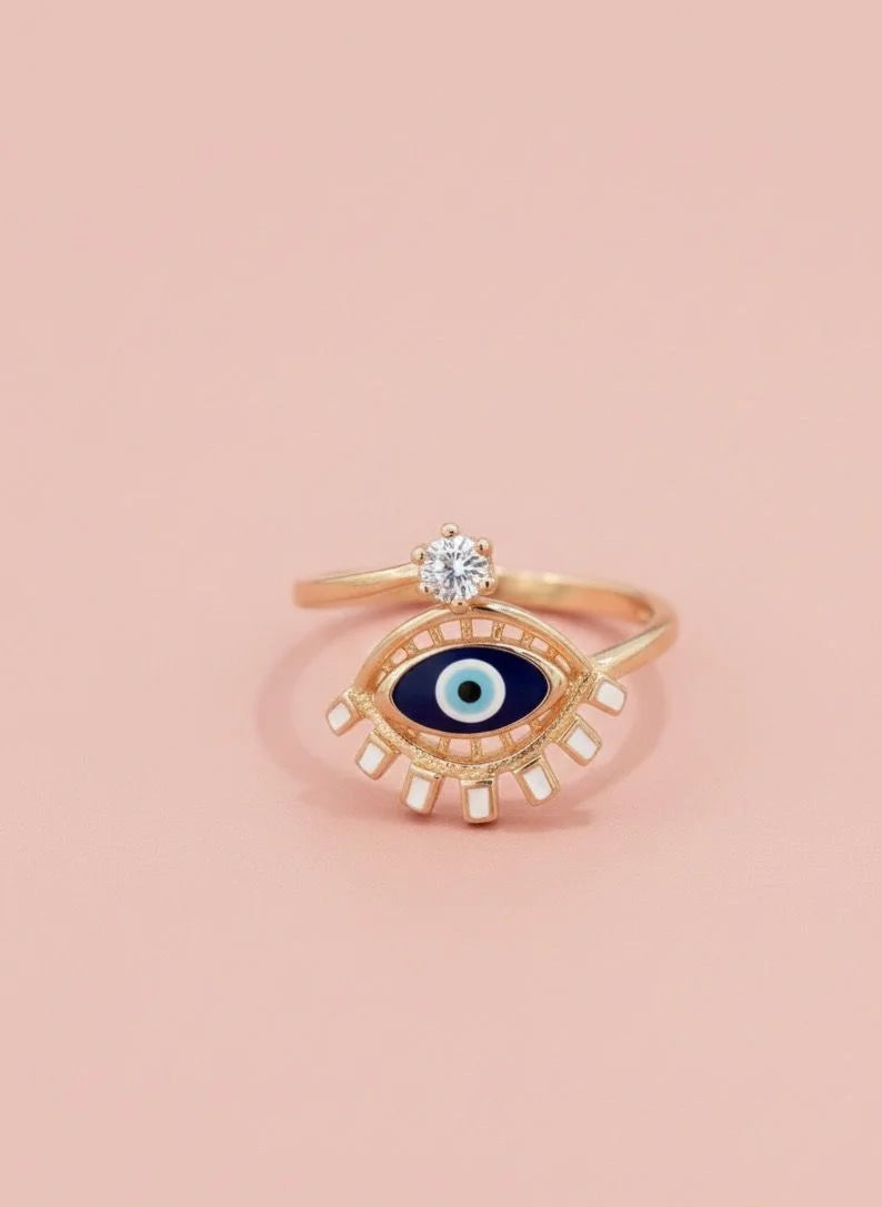 Gold ring with eye design on a pink background