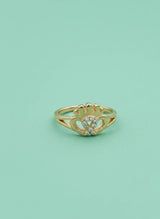Gold ring with a heart design on a light green background