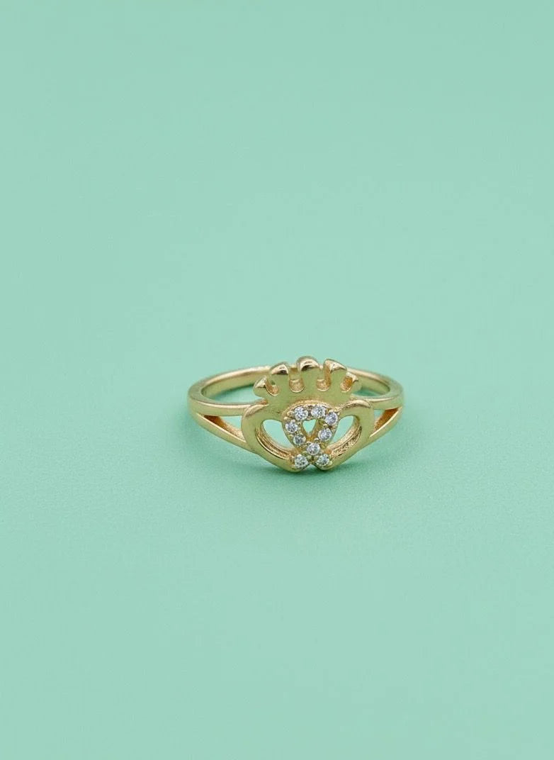 Gold ring with a heart design on a light green background