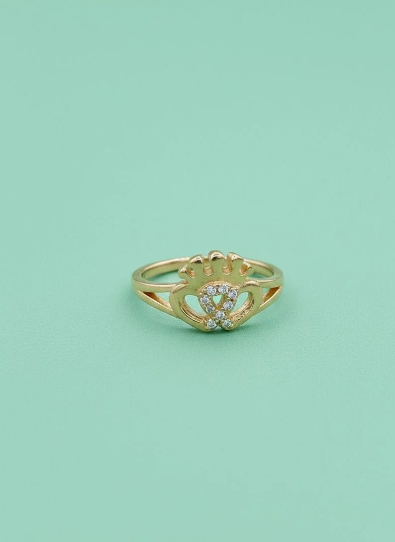 Gold ring with a heart design on a light green background