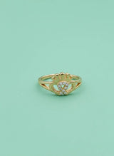 Gold ring with a heart design on a light green background