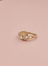Gold ring with a yellow gemstone on a pink background