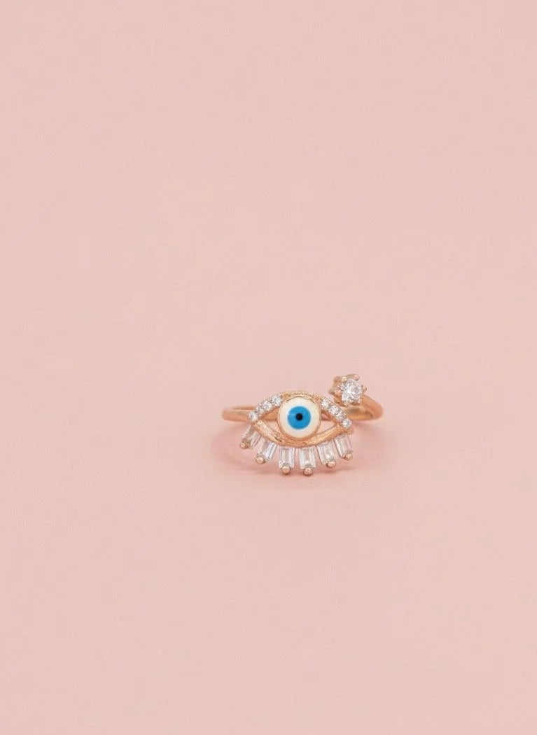 Rose gold ring with a blue gemstone on a pink background