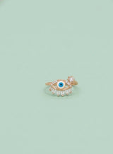 Gold ring with eye design on a light green background