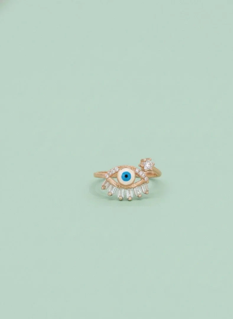 Gold ring with eye design on a light green background