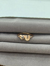 Gold ring with heart and 'U' design on a gray surface
