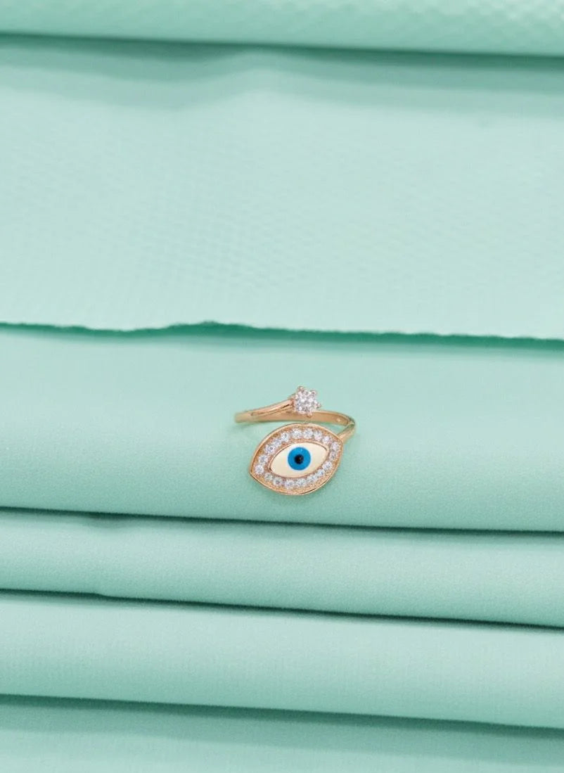 Gold ring with a blue gemstone on a stack of light green fabric