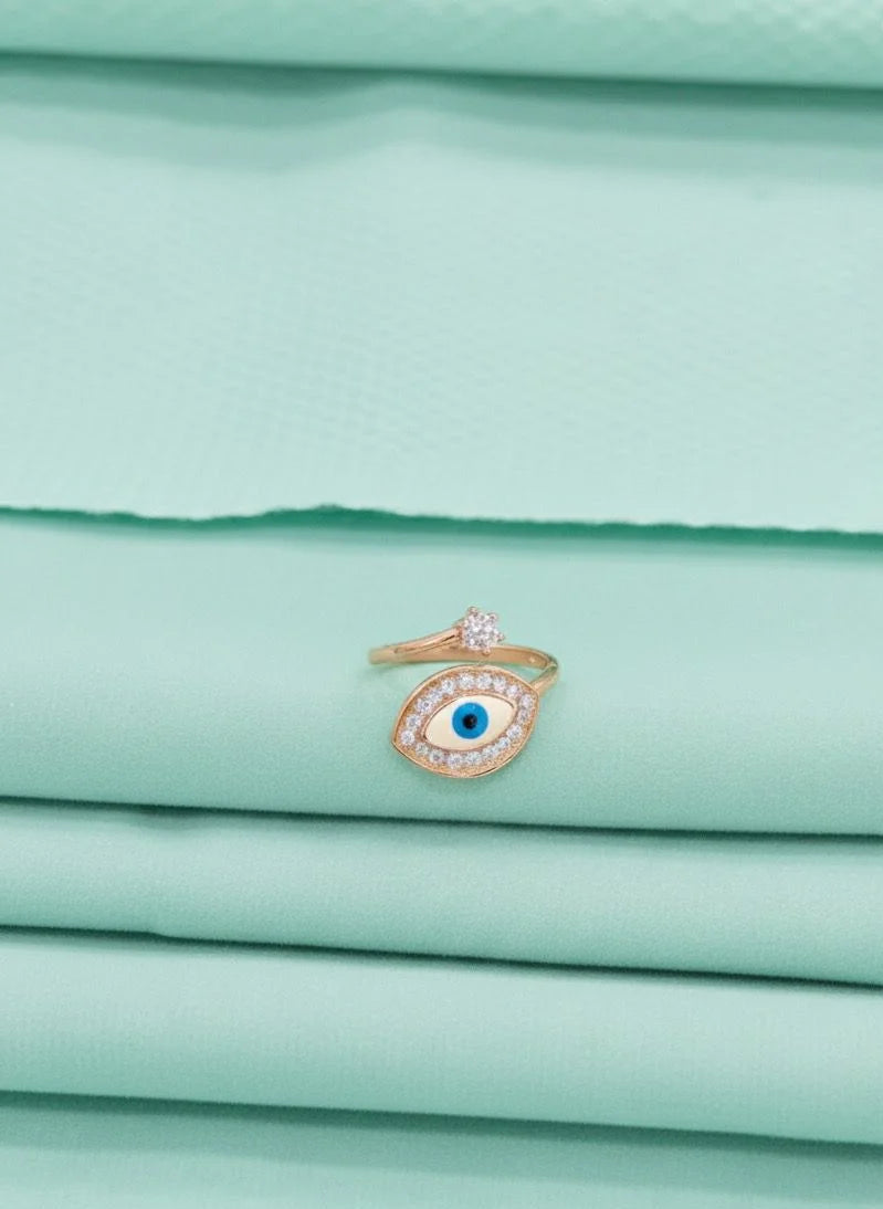 Gold ring with a blue gemstone on a stack of light green fabric