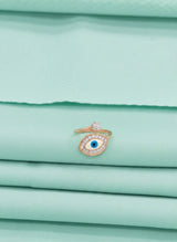 Gold ring with a blue gemstone on a stack of light green fabric