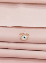 Rose gold ring with a blue gemstone on a pink fabric background