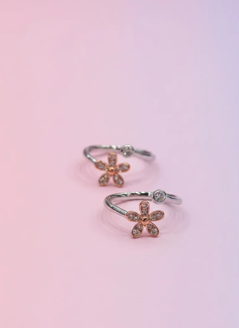 Flower-shaped toe rings on a gradient pink background
