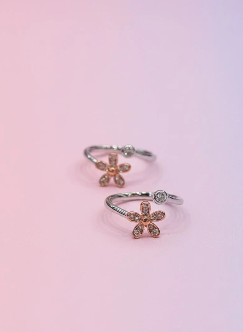Flower-shaped toe rings on a gradient pink and purple background