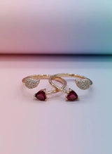 Gold toe ring with red gemstones on a gradient background
