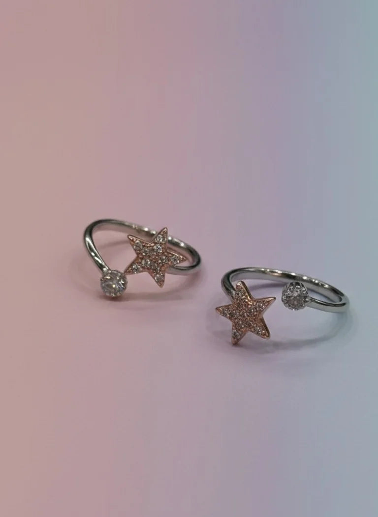 Two star-shaped toe rings with small diamonds on a gradient background