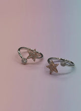 Two star-shaped toe rings with small diamonds on a gradient background
