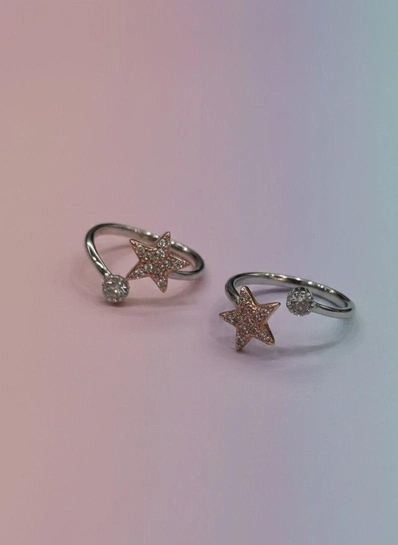 Two star-shaped toe rings with gemstones on a gradient background