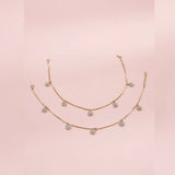 Rose gold anklet with diamond-like stones on a pink background
