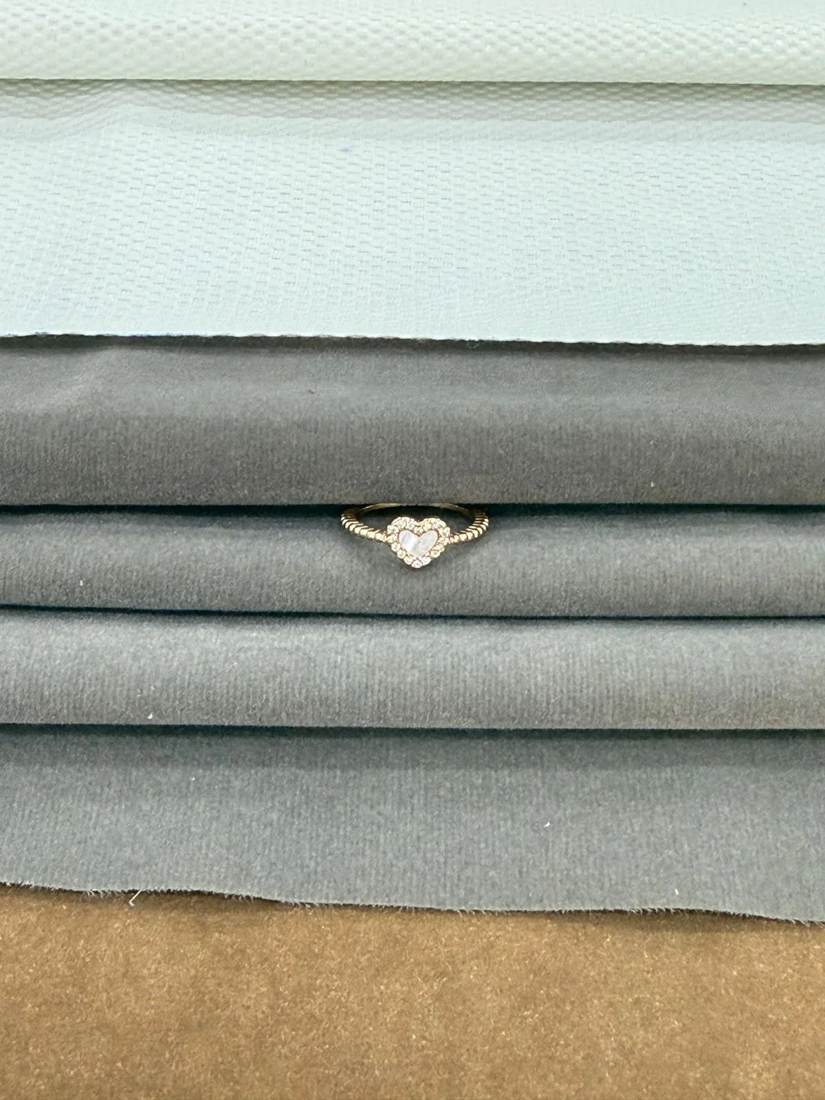 Stack of fabric swatches in various colors with a heart-shaped ring on top.