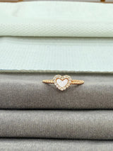 Heart-shaped ring with pink gemstone on a stack of gray fabric