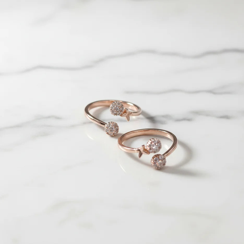 Rose gold toe ring with embedded stones on a marble surface