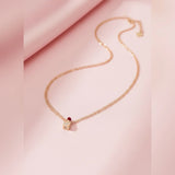 Rose gold necklace with a lipstick pendant on a pink fabric background